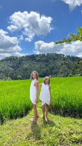 dos chicas con vestidos blancos de pie en un campo en Pondok Masa Depan, en Sidemen