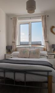 a bedroom with a large bed with two windows at Hegarty's cottage at Trevarrian Lodge in Mawgan Porth