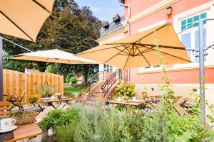 un patio avec des tables et des parasols dans un jardin dans l'établissement Parkhotel Jever, à Jever