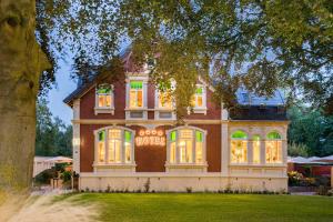 a large brick house with lit up windows at Parkhotel Jever in Jever