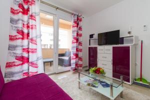 ein Wohnzimmer mit einem lila Sofa und einem TV in der Unterkunft Apartment Vodice 16249b in Vodice