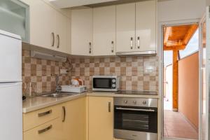 a kitchen with white cabinets and a sink and a microwave at Apartments by the sea Vodice - 16249 in Vodice