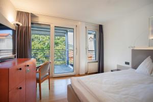 1 dormitorio con cama, escritorio y ventana en GUESTHOUSE ZURZACH - Self Check-in, en Bad Zurzach