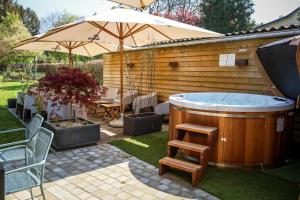 a hot tub in a yard with an umbrella at LA GLORIETTE in Marche-en-Famenne