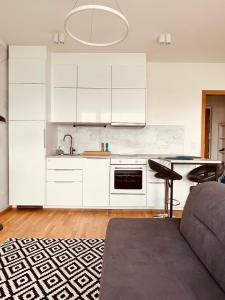 a kitchen with white cabinets and a table and a couch at White Pearl Studio with parking in Holešovice in Prague