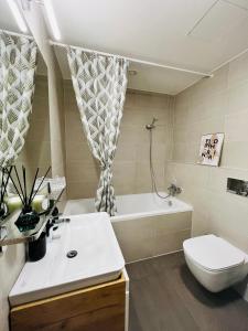 uma casa de banho com um lavatório, uma banheira e um WC. em White Pearl Studio with parking in Holešovice em Praga