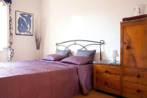 a bedroom with a bed with purple sheets and a dresser at Maison Dei Miracoli in Pisa