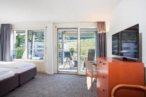Pokój hotelowy z łóżkiem, biurkiem i telewizorem w obiekcie GUESTHOUSE ZURZACH - Self Check-in w mieście Bad Zurzach