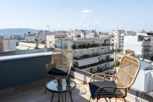 three chairs and a table on a balcony with a view at Empress Luxury Residences in Volos