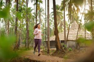 a woman running through a forest with palm trees at Sarth Ayurveda Retreat and Wellness Centre in Sawantwadi