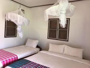 - 2 lits dans une chambre avec fenêtres et rideaux dans l'établissement Konglor Eco-Lodge Guesthouse and Restaurant, à Ban O