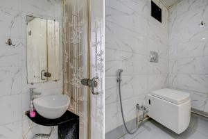a white bathroom with a toilet and a sink at FabHotel Vardhan House in Pune