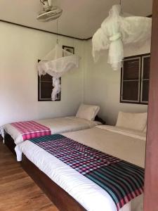 Duas camas num quarto com paredes brancas em Konglor Eco-Lodge Guesthouse and Restaurant em Ban O