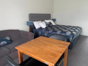 a living room with a couch and a table and a bed at Orbost Country Man Motor Inn in Orbost