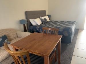 Orbost Country Man Motor Inn في أوربوست: غرفة معيشة مع طاولة خشبية وسرير