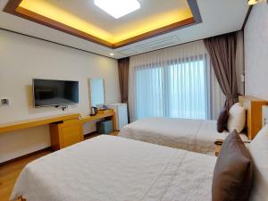 a hotel room with two beds and a flat screen tv at Fellisia Hotel in Seogwipo