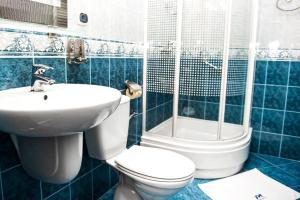 a blue tiled bathroom with a toilet and a sink at Hotel Manhatan 