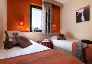 two beds in a room with orange walls and a window at Résidence Pierre & Vacances Premium L'Amara in Avoriaz