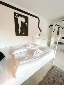 uma cama branca num quarto branco com uma fotografia na parede em Ginius Homes - Eifelglück im Grünen em Kall