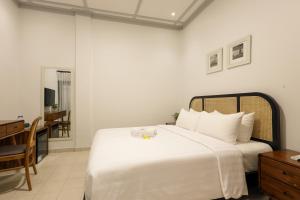 a bedroom with a large white bed and a desk at CERIA HOTEL at Alun Alun Yogyakarta in Yogyakarta