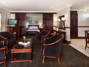 um quarto de hotel com uma cama e uma sala de estar em Court Classique Suite Hotel em Pretoria
