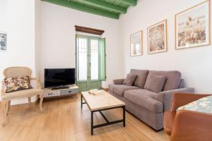 een woonkamer met een bank en een tv bij Charming apartment at La Alameda Seville City Center by Oui Sevilla in Sevilla