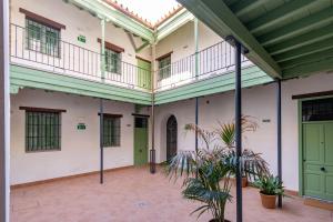 een lege binnenplaats van een gebouw met groene deuren en planten bij Charming apartment at La Alameda Seville City Center by Oui Sevilla in Sevilla