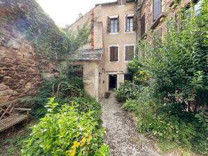 an alley way in an old building with plants at Le Place Du Bourg Appartement T2 Centre Historique Rodez in Rodez