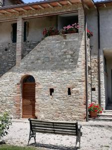 un banco frente a un edificio con puerta en Fattoria di Rigone, en Coltavolino