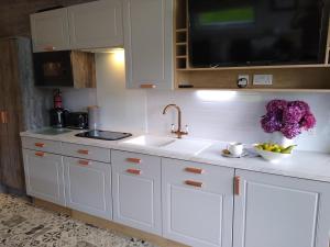 a kitchen with white cabinets and a sink and purple flowers at The Cuddies in Balloch