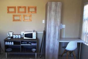 a room with a desk with a microwave and a chair at Cenikma Guest Suites - Couples Room in East London