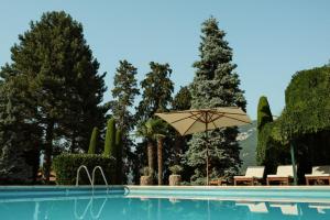 una piscina con sombrilla, sillas y árboles en Wirnica, en Garlate