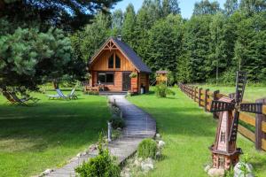 a log cabin in a yard with a wooden path leading to it at Holandiesi Holiday House in Ķesterciems