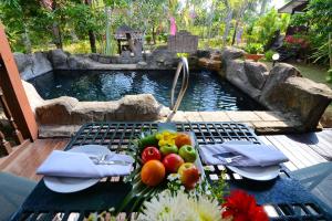 a picnic table with fruit on it next to a pond at LaVilla By Holiday Villa Cherating in Cherating