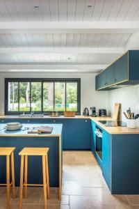una cocina con armarios azules y 2 taburetes. en Belle villa rétaise 4 étoiles avec piscine chauffée, en La Couarde-sur-Mer