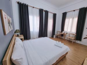 a bedroom with a large white bed with black curtains at Hidden Hue Homestay in Hue