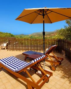 a lounge chair and an umbrella on a patio at Residenza Su Prelau in Gonnesa