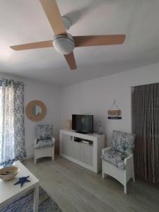 a living room with a ceiling fan and two chairs at Flamenco playa in El Puerto de Santa María