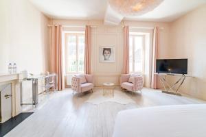 een slaapkamer met een bed en twee stoelen en een televisie bij Villa Ribière in Auxerre