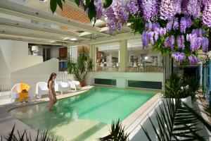 a woman standing next to a swimming pool in a building at Hotel Romagna in Cattolica +152 photos