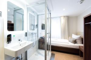 a bathroom with a sink and a shower and a bed at Arena am Zoo in Frankfurt