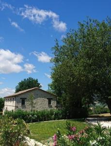 una casa de piedra en un jardín con un árbol en Valcastagno Relais, en Sirolo