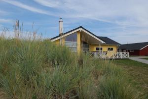 una casa amarilla en una playa con hierba alta en Resort 2 Ferienhaus Typ D 122, en Großenbrode