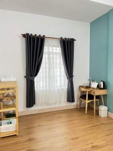 a room with a window with black curtains and a desk at Hidden Hue Homestay in Hue