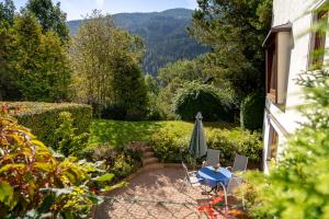 a patio with a table and an umbrella in a garden at Heimeliges Apartment in den Bergen in Bad Kleinkirchheim