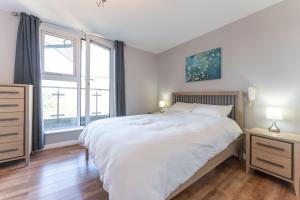 1 Schlafzimmer mit einem großen weißen Bett und 2 Fenstern in der Unterkunft Luxury 2 Bed Apartment Parking by NEC & Solihull in Solihull