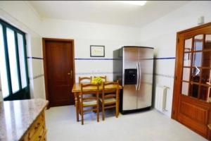 a kitchen with a table and a stainless steel refrigerator at Azeitao Idílica Moradia T4 no Descanso do Campo in Setúbal +4 photos