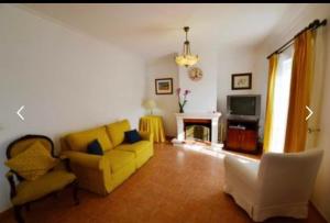 a living room with a yellow couch and a tv at Azeitao Idílica Moradia T4 no Descanso do Campo in Setúbal