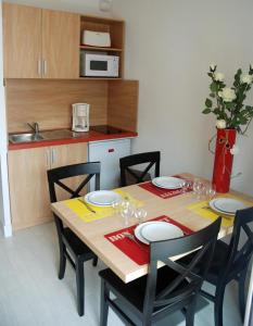a dining room table with chairs and a kitchen at Résidence Goélia Le Grand Bleu in Le Barcarès