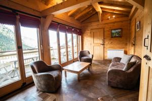 ein Wohnzimmer mit Sofas, einem Tisch und Fenstern in der Unterkunft Chalet LouBochu Châtel Réservation in Châtel